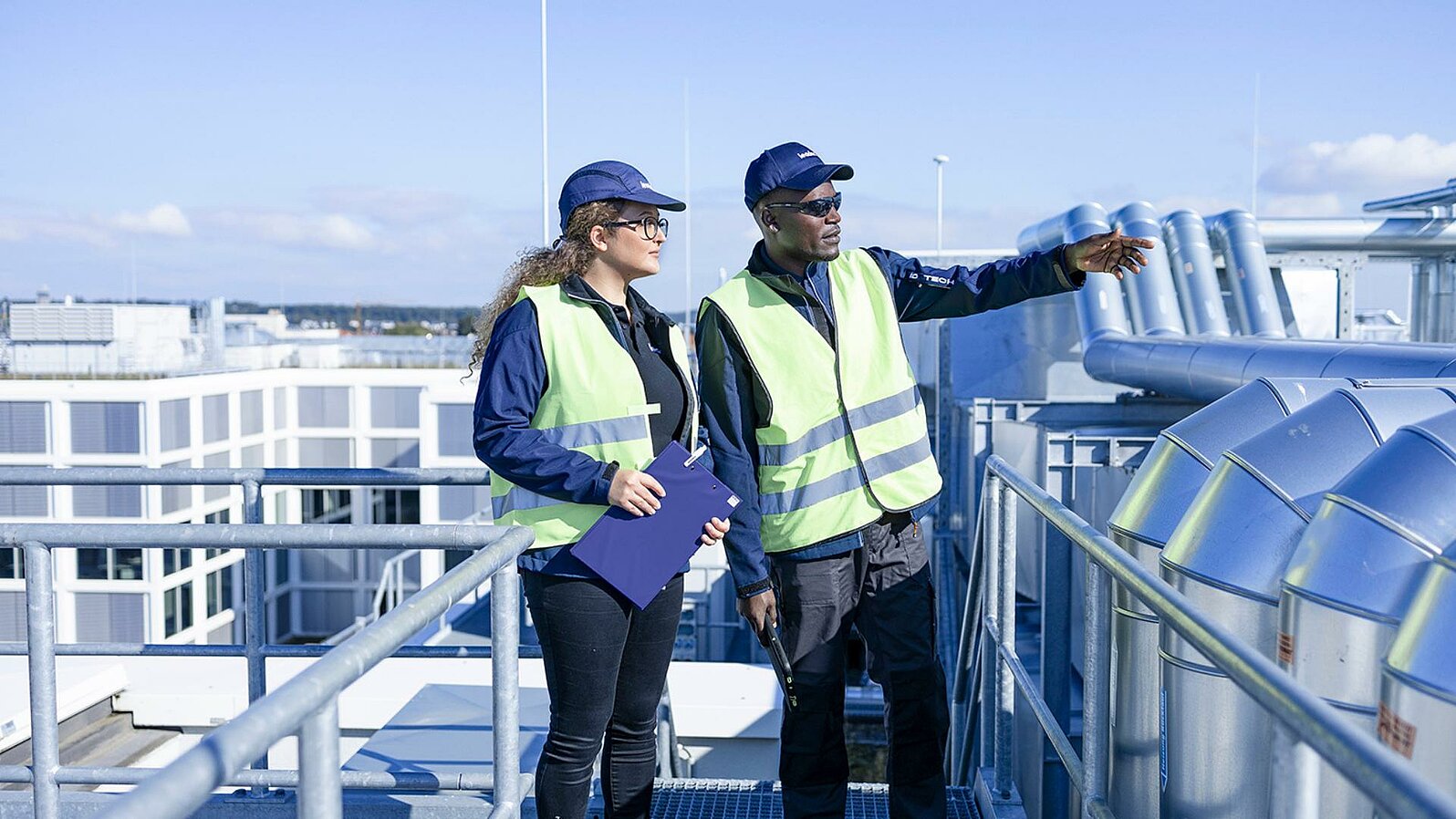 Two Leadec employees inspecting pipes on a factory roof.
